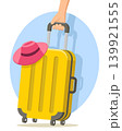 Yellow suitcase with a hat pulled by a woman s hand on a white background. Travel suitcase 139921555