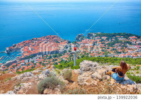 Girl enjoys view of old town (medieval Ragusa) and Dalmatian Coast of Adriatic Sea in Dubrovnik Girl enjoys view of old town (medieval Ragusa) and Dalmatian Coast of Adriatic Sea in Dubrovnik 139922036