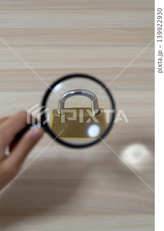虫眼鏡で拡大した南京錠を調べる手元 虫眼鏡で拡大した南京錠を調べる手元 139922930