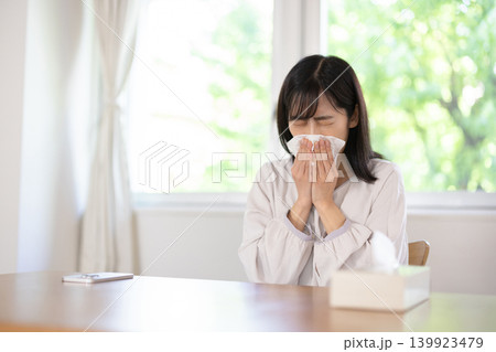 明るいリビングルームで鼻をかむ日本人の若い女性 139923479