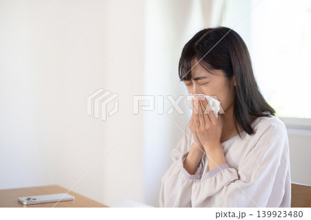 明るいリビングルームで鼻をかむ日本人の若い女性 139923480