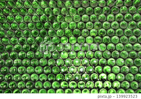 Full frame wall with empty green beer bottles bottoms. Alcohol theme. Endless rows of wine bottles. Green glass bottle wall with sunlight from behind Full frame wall with empty green beer bottles bottoms. Alcohol theme. Endless rows of wine bottles. Green glass bottle wall with sunlight from behind 139923523
