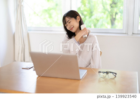 マッサージガンで肩をセルフマッサージする日本人の若い女性 139923540