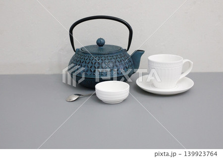Tea preparation with a teapot, tea bag, cup, bowl, and spoon on a table in a simple setting Tea preparation with a teapot, tea bag, cup, bowl, and spoon on a table in a simple setting 139923764