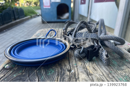 Dog walking items left on a wooden table near a trash can in an outdoor area Dog walking items left on a wooden table near a trash can in an outdoor area 139923768