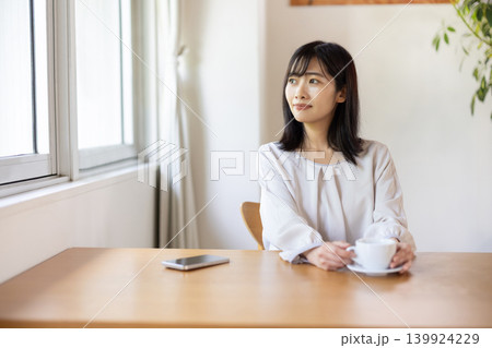 窓際のテーブルでコーヒーを楽しむ日本人の若い女性 窓際のテーブルでコーヒーを楽しむ日本人の若い女性 139924229