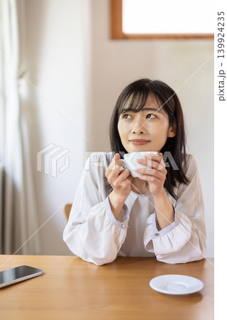 窓際のテーブルでコーヒーを楽しむ日本人の若い女性 窓際のテーブルでコーヒーを楽しむ日本人の若い女性 139924235