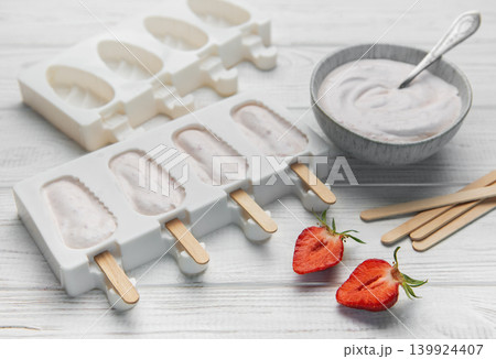 Preparing homemade strawberry popsicles in silicone molds Preparing homemade strawberry popsicles in silicone molds 139924407