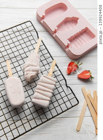 Homemade strawberry popsicles drying on cooling rack Homemade strawberry popsicles drying on cooling rack 139924408