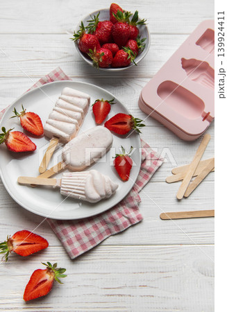 Homemade strawberry popsicles on white wooden table 139924411