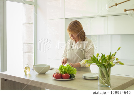 Female person with healthy food in kitchen. Woman 45 years old lifestyle portrait Female person with healthy food in kitchen. Woman 45 years old lifestyle portrait 139924646