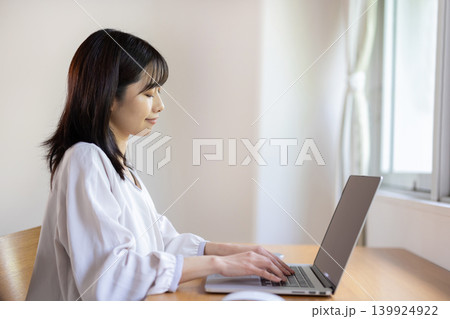 明るい窓際のテーブルでパソコン作業をする日本人の若い女性 明るい窓際のテーブルでパソコン作業をする日本人の若い女性 139924922
