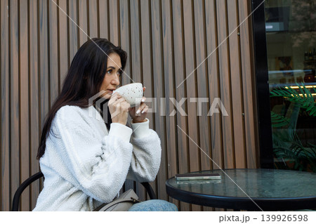 Pretty woman drinking coffee in city street cafe outdoors Pretty woman drinking coffee in city street cafe outdoors 139926598