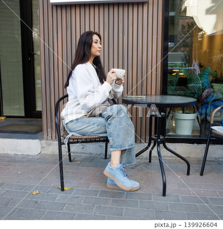 Cheerful woman drinking coffee in city street cafe outdoors 139926604