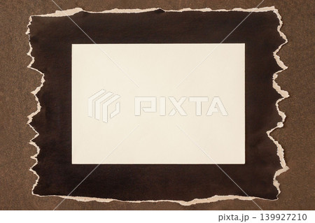 Blank empty card on Torn Black Paper Background. Blank white textured card placed on torn black paper over brown surface, top view above. Minimal paper mockup, rough edges, copy space for notes 139927210