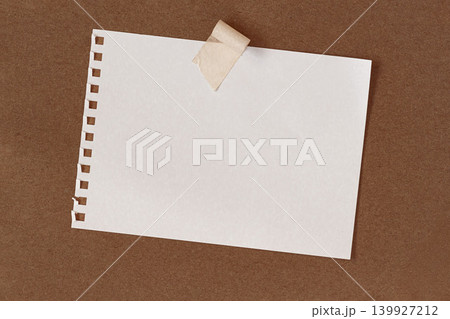 White paper sheet taped on brown cardboard surface with copy space for note, message, list, mockup. Natural textured paper background. Office, school, reminder, planning, design concept White paper sheet taped on brown cardboard surface with copy space for note, message, list, mockup. Natural textured paper background. Office, school, reminder, planning, design concept 139927212