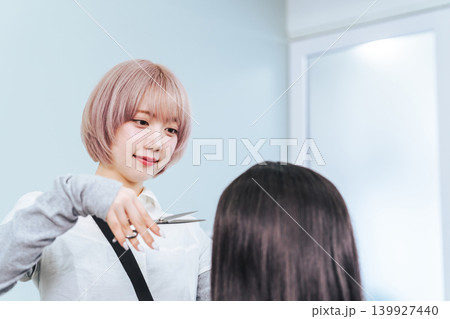 ヘアカットするハイトーンヘアの女性スタッフ ヘアカットするハイトーンヘアの女性スタッフ 139927440