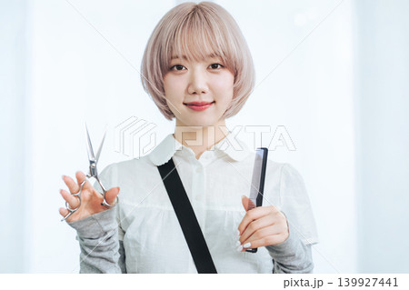 ヘアカット道具を持つハイトーンヘアの女性スタッフ 139927441