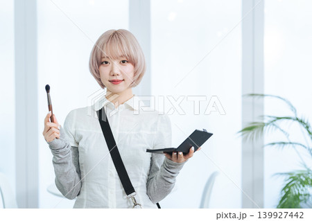ヘアメイク道具を持つハイトーンヘアの女性スタッフ 139927442
