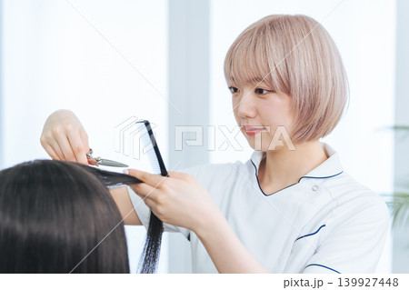 ヘアカットするハイトーンヘアの女性スタッフ 139927448