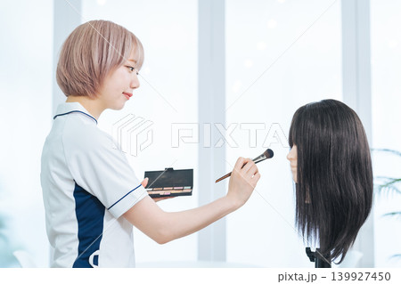 メイクするハイトーンヘアの女性スタッフ メイクするハイトーンヘアの女性スタッフ 139927450