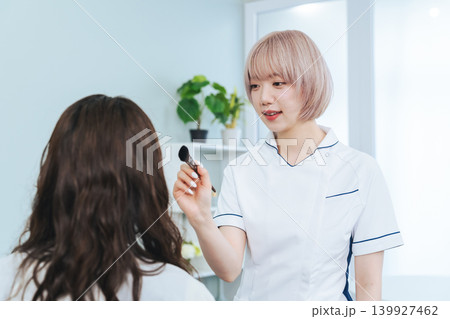 メイクするハイトーンヘアの女性スタッフ メイクするハイトーンヘアの女性スタッフ 139927462
