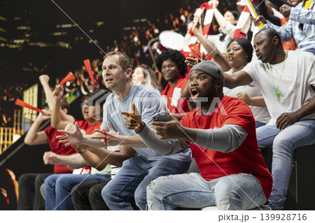Diverse football fans following live score for betting odds on phone, cheering and watching intense soccer match at stadium. Supporters use mobile betting app for high risk wager, sports betting. Diverse football fans following live score for betting odds on phone, cheering and watching intense soccer match at stadium. Supporters use mobile betting app for high risk wager, sports betting. 139928716