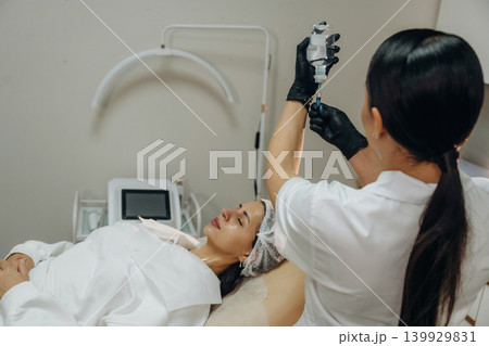 Taking the product by syringe. Cosmetologist performing a facial injection procedure in a beauty clinic Taking the product by syringe. Cosmetologist performing a facial injection procedure in a beauty clinic 139929831