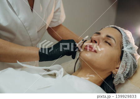 Ready to penetrate the skin. Cosmetologist performing a facial injection procedure in a beauty clinic 139929833