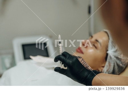 Ready to penetrate the skin. Cosmetologist performing a facial injection procedure in a beauty clinic 139929836