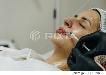 Ready to penetrate the skin. Cosmetologist performing a facial injection procedure in a beauty clinic Ready to penetrate the skin. Cosmetologist performing a facial injection procedure in a beauty clinic 139929839