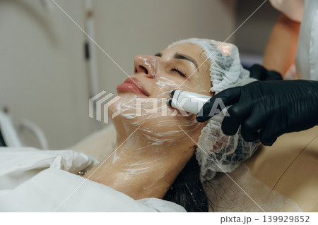 With eyes closed. Close-up of a facial skincare treatment with a cosmetic device in a beauty clinic With eyes closed. Close-up of a facial skincare treatment with a cosmetic device in a beauty clinic 139929852