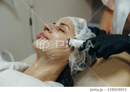 With eyes closed. Close-up of a facial skincare treatment with a cosmetic device in a beauty clinic With eyes closed. Close-up of a facial skincare treatment with a cosmetic device in a beauty clinic 139929853