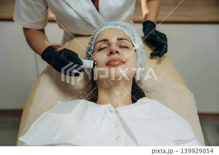 With eyes closed. Close-up of a facial skincare treatment with a cosmetic device in a beauty clinic 139929854