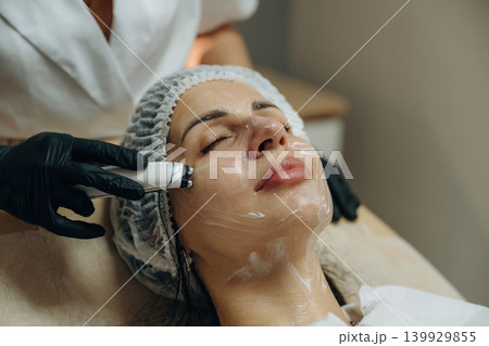 With eyes closed. Close-up of a facial skincare treatment with a cosmetic device in a beauty clinic With eyes closed. Close-up of a facial skincare treatment with a cosmetic device in a beauty clinic 139929855