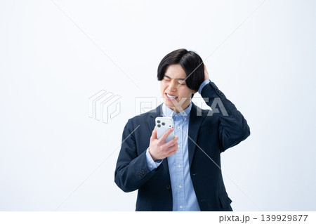スマホを持って困った表情のビジネスマン スマホを持って困った表情のビジネスマン 139929877