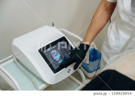 A close-up view of a cosmetologist performing a facial skincare procedure using a cosmetic device in a beauty clinic 139929954
