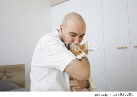 Portrait of man holding fluffy cat pet and having fun together at home Portrait of man holding fluffy cat pet and having fun together at home 139930290