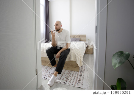 Man dictates a voice message on a smartphone at home 139930291