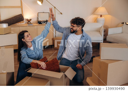 Great teamwork, high five. Playful couple enjoying time together while moving into a new home Great teamwork, high five. Playful couple enjoying time together while moving into a new home 139930490