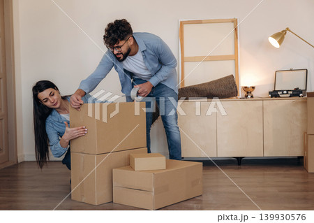 Using scotch as glue. Couple packing cardboard boxes while preparing to move into a new home Using scotch as glue. Couple packing cardboard boxes while preparing to move into a new home 139930576
