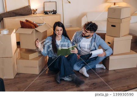Notepad is in hands. Couple reviewing documents and planning their new home after moving Notepad is in hands. Couple reviewing documents and planning their new home after moving 139930590