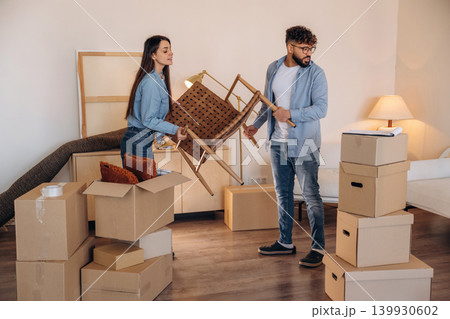 Chair is in hands. Couple packing while preparing to move into a new home Chair is in hands. Couple packing while preparing to move into a new home 139930602