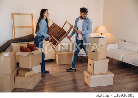 Chair is in hands. Couple packing while preparing to move into a new home 139930603