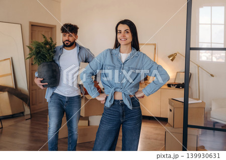 Positive couple placing a potted plant in their new apartment during the moving process Positive couple placing a potted plant in their new apartment during the moving process 139930631