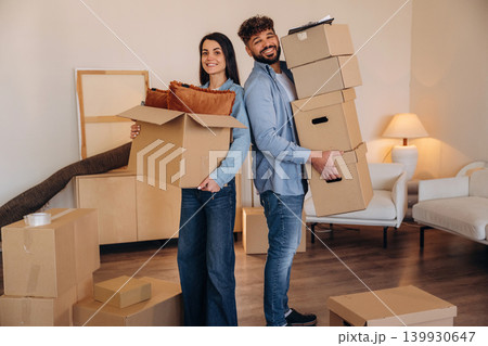 Standing together. A couple carrying cardboard boxes while moving into a new apartment 139930647