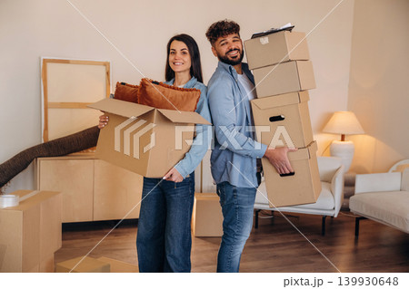 Standing together. A couple carrying cardboard boxes while moving into a new apartment 139930648