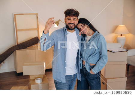 Positive facial expression. Excited couple holding house keys after moving into their new home 139930650