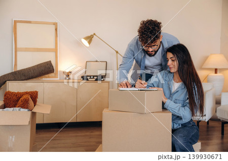Focused, writing on the paper. Couple reviewing documents and planning their new home after moving 139930671