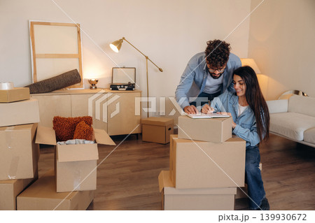 Focused, writing on the paper. Couple reviewing documents and planning their new home after moving Focused, writing on the paper. Couple reviewing documents and planning their new home after moving 139930672